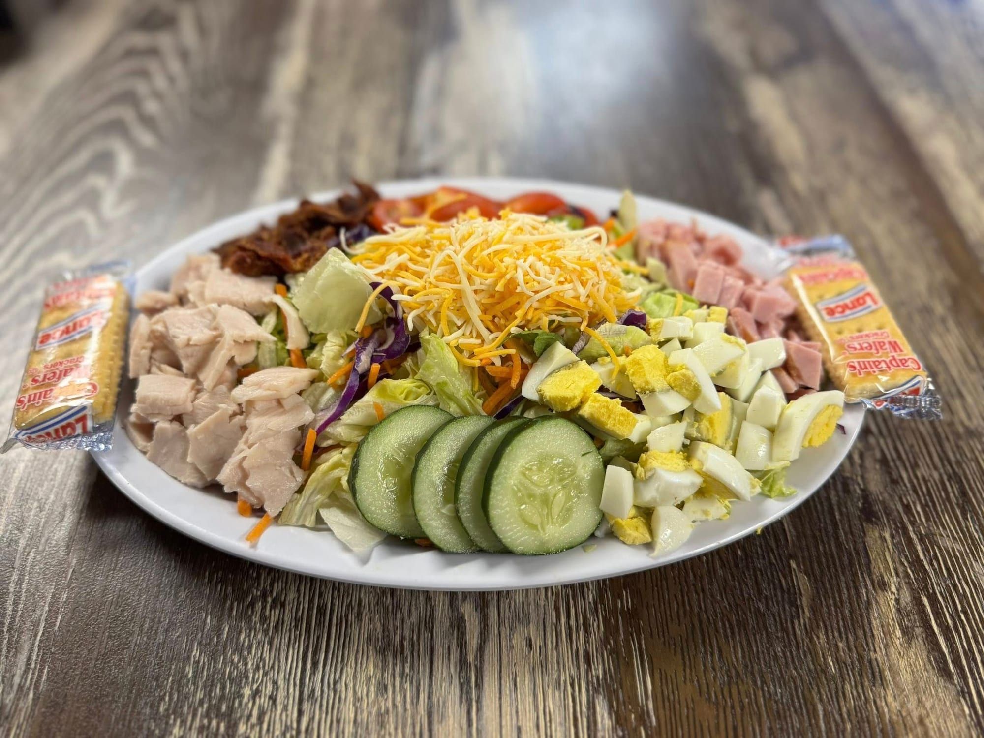 A chef salad with turkey, ham, egg, cheese and cucumber